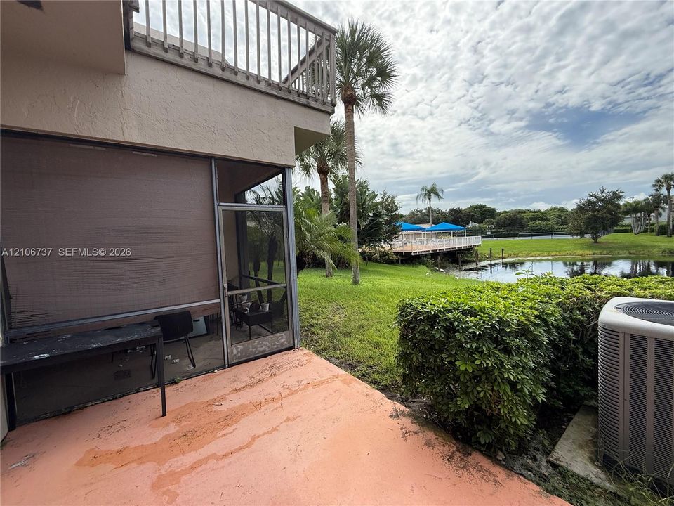 Screened-in patio with concrete flooring, second-story balcony with metal railings, and exterior water frontage