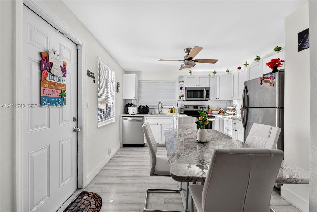 Kitchen featuring white cabinetry, stainless steel appliances, wood-finish flooring, and a ceiling fan