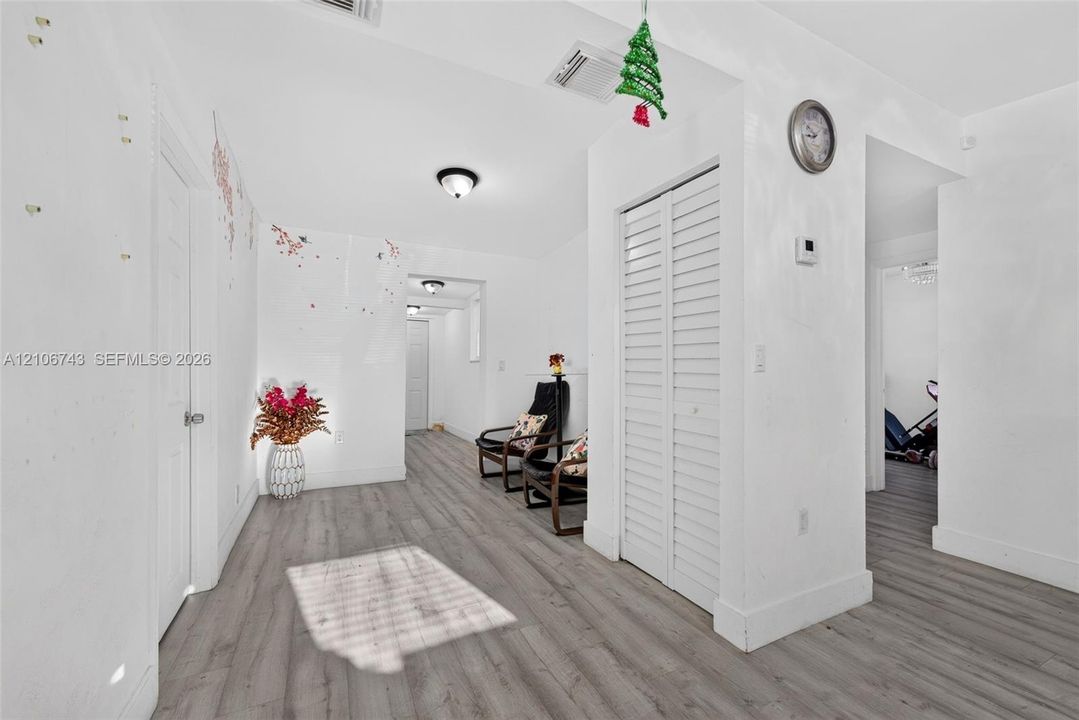 Wood-finish flooring, white paneled interior doors, and closet featuring white louvered doors