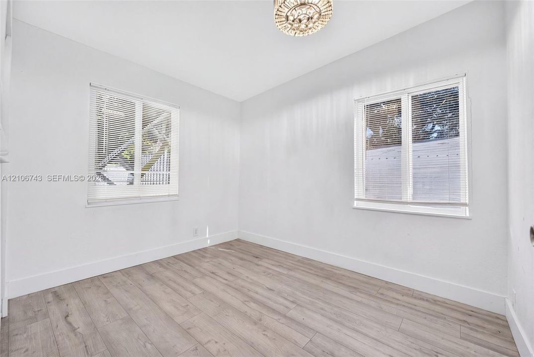 Interior room featuring wood-finish flooring, two windows with horizontal blinds, and a drum-style ceiling light fixture
