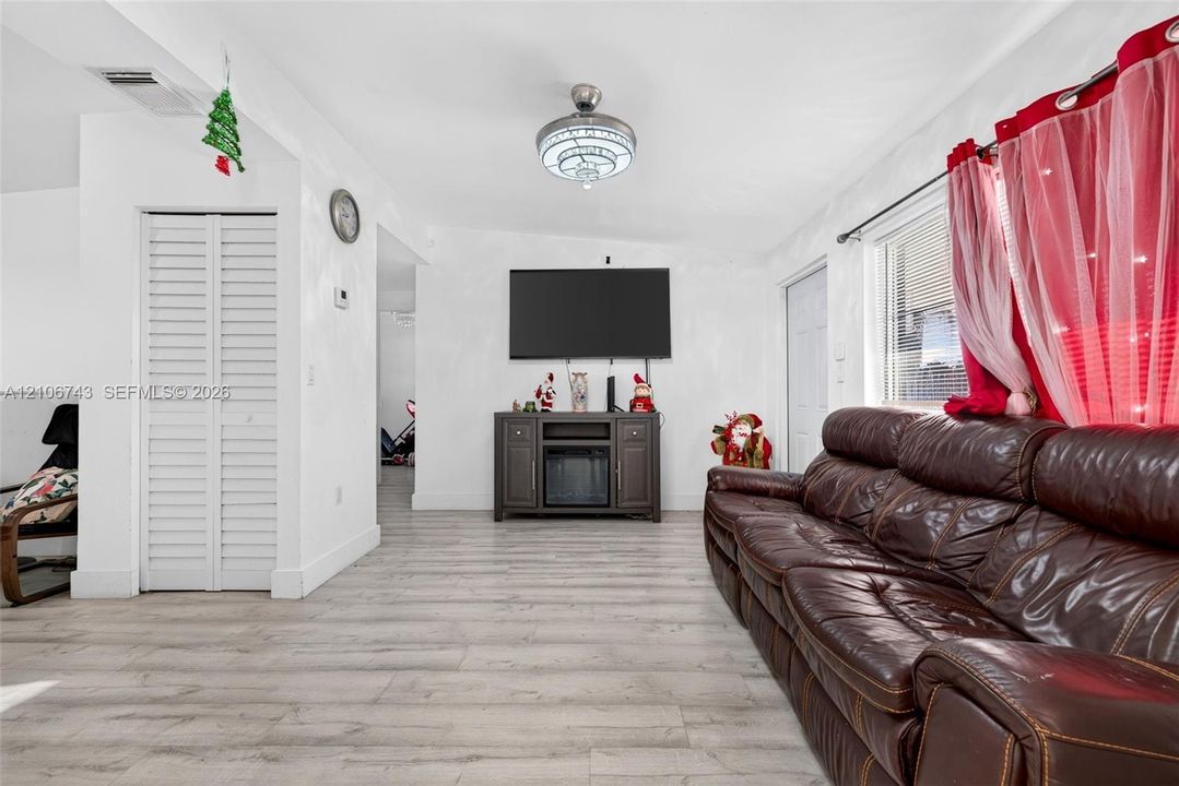 Wood-finish flooring, white walls, louvered bi-fold closet door, and a circular drum-style flush-mount light fixture