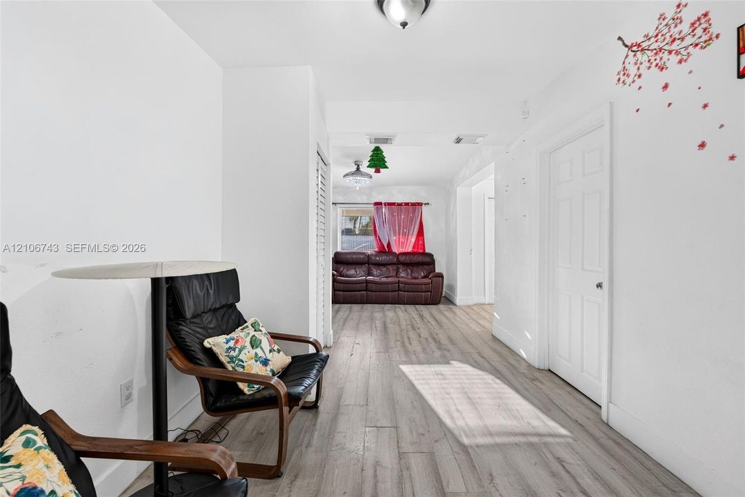 Interior space featuring wood-finish flooring, white walls, and a multi-panel door with brushed metal hardware