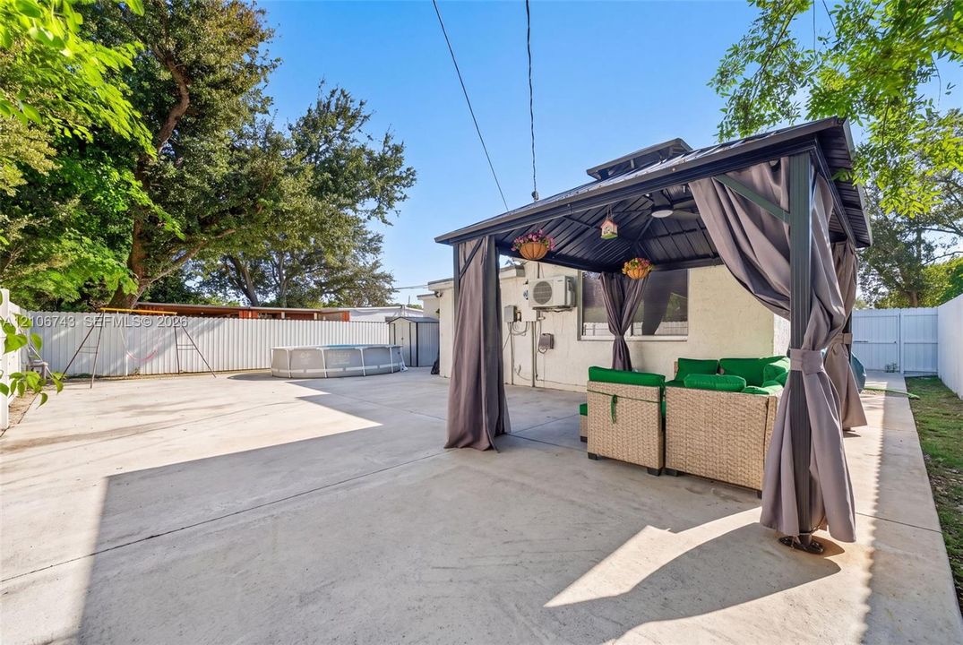 Backyard featuring an expansive concrete patio, a metal-framed gazebo, and perimeter privacy fencing