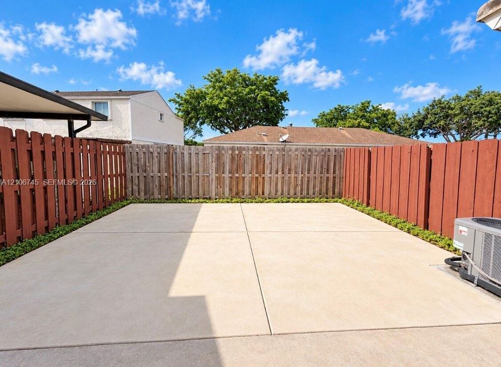 Concrete patio enclosed by wood privacy fencing and low-profile perimeter shrubbery