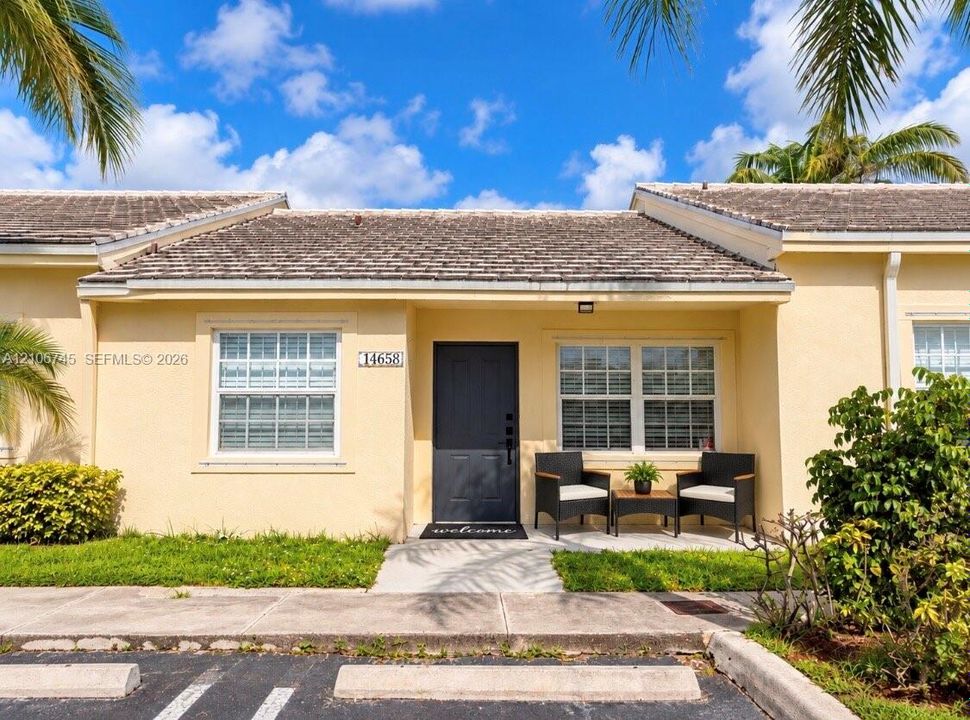 Stucco exterior featuring a shake-style roof, covered entryway, and multi-pane windows