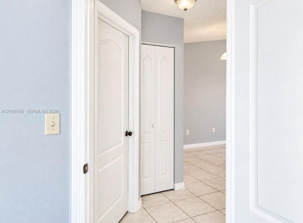 Neutral wall tones featuring white interior doors with arched-top panels, tile flooring, and bi-fold closet doors