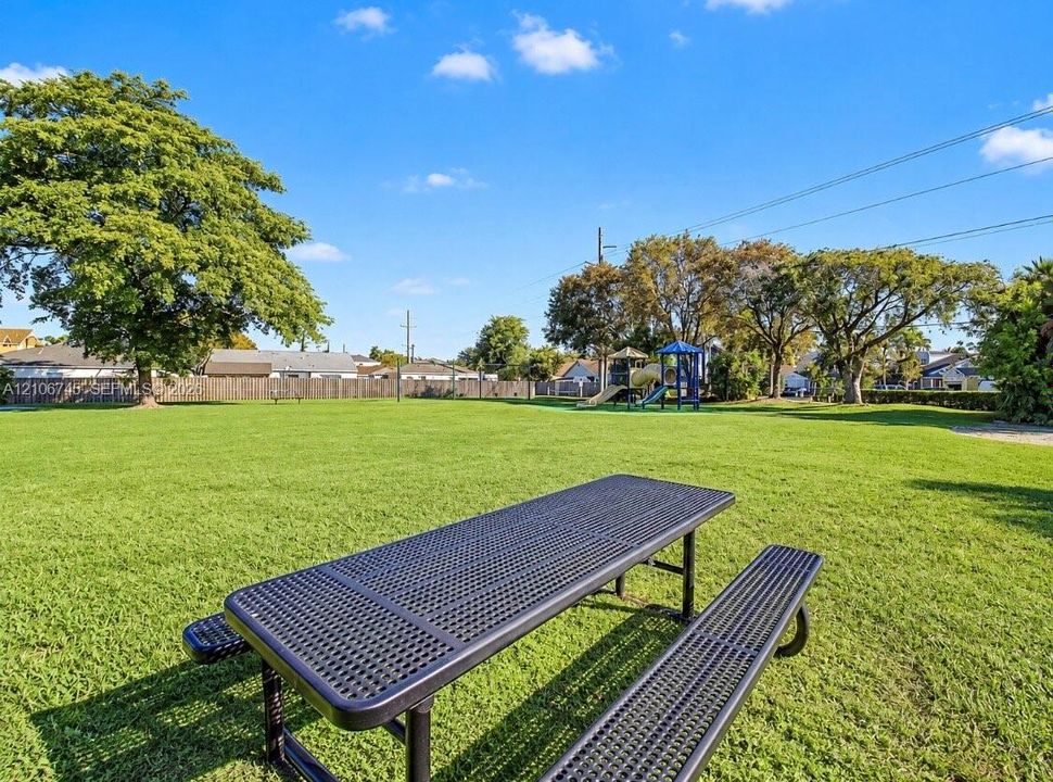 Expansive lawn featuring mature trees, wood privacy fencing, and a permanent metal picnic table