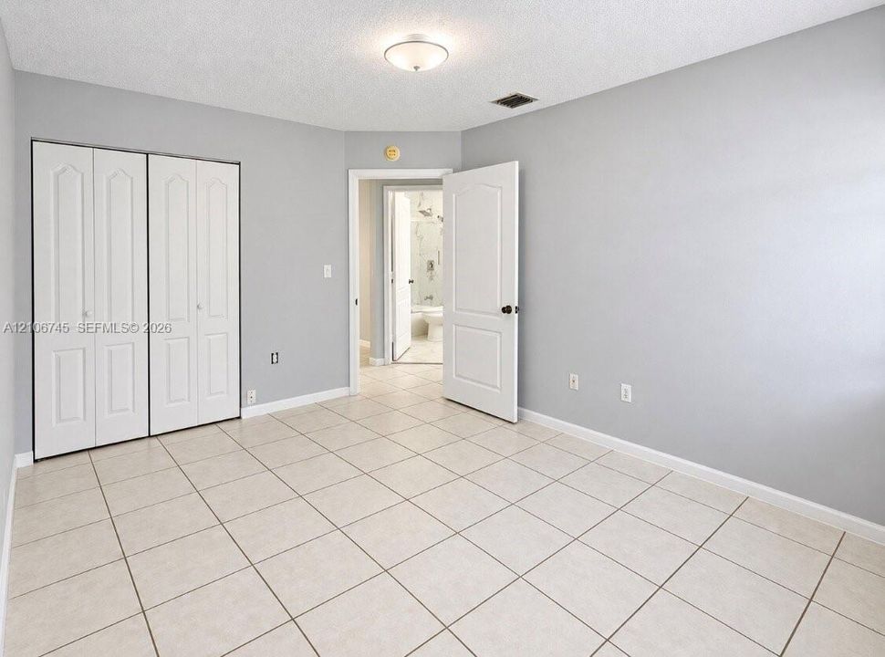 Neutral interior featuring light-toned tile flooring, white bi-fold closet doors, a neutral wall color palette, and a semi-flush mount ceiling fixture