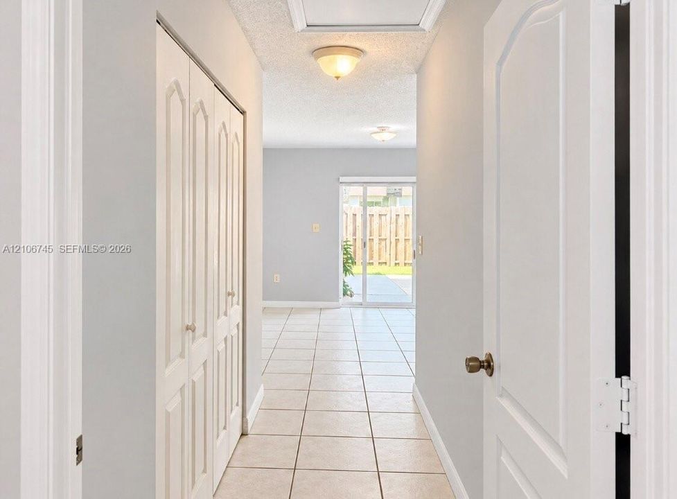Hallway featuring neutral-toned tile flooring, bi-fold closet doors, and sliding glass exterior doors