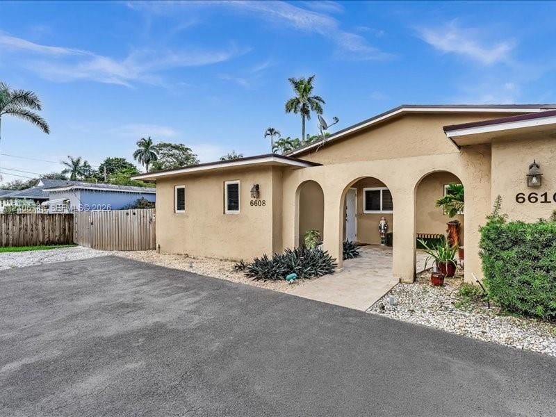 Stucco exterior featuring dual arched entryways, a paved driveway, and decorative exterior wall-mounted lighting