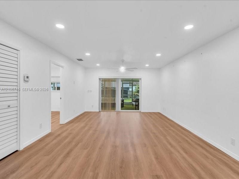 Spacious room featuring wood-finish flooring, recessed lighting, a ceiling fan, and sliding glass doors leading to an enclosed outdoor area