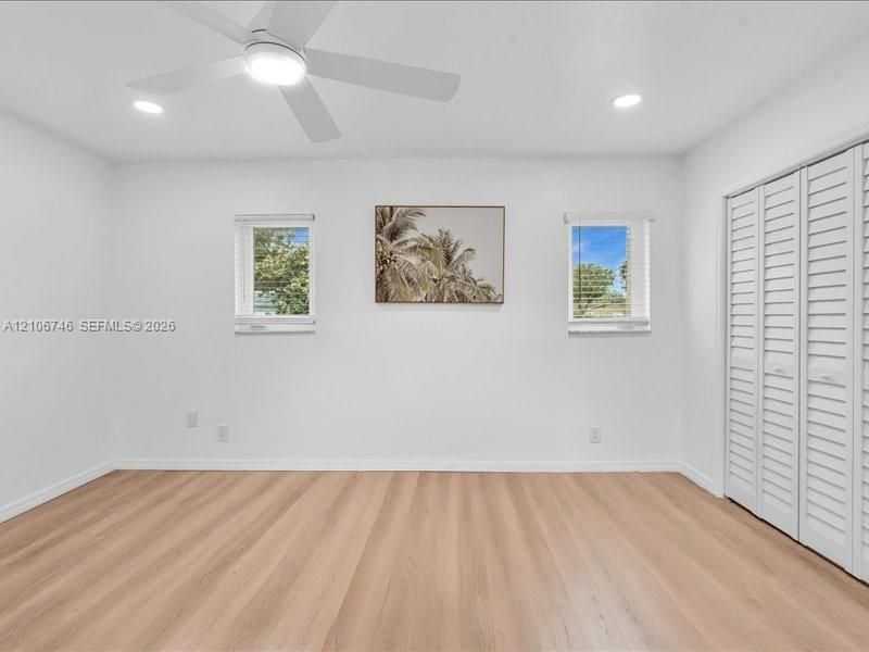 Neutral interior featuring wood-finish flooring, recessed lighting, a modern ceiling fan, and white louvered closet doors