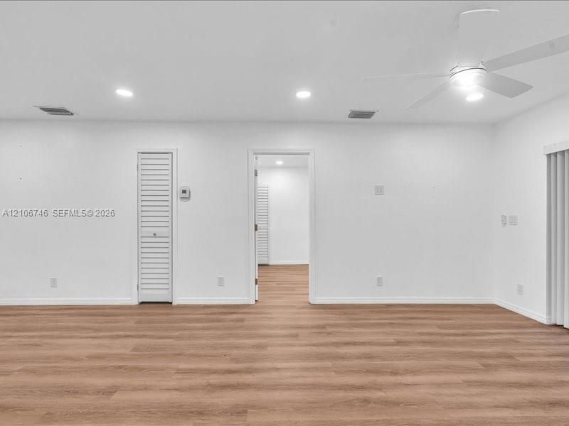 Neutral interior space featuring wood-finish flooring, recessed lighting, a white ceiling fan, and a louvered closet door