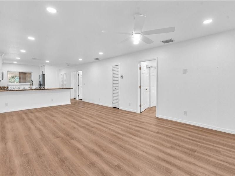 Open-concept interior featuring wood-finish flooring, recessed lighting, a ceiling fan, and a breakfast bar