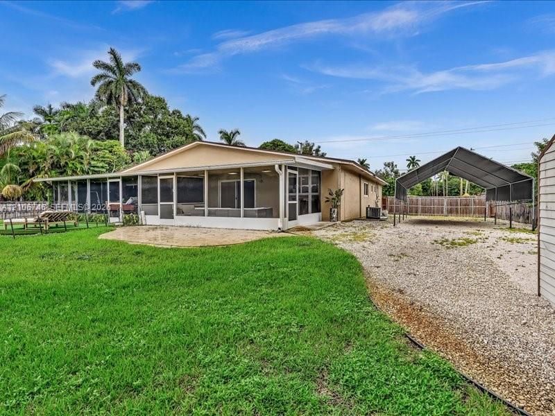 Exterior featuring a screened-in patio, concrete paver patio, metal-frame carport, and perimeter wood fencing