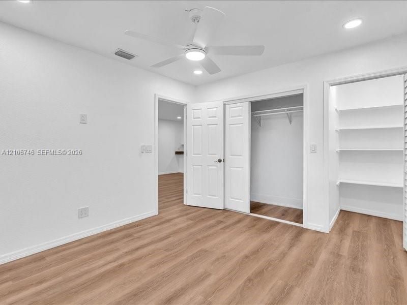 Wood-finish flooring, recessed lighting, ceiling fan with integrated light, closet with double doors, and built-in shelving