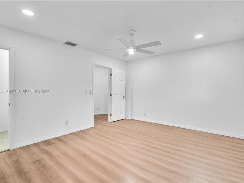 Neutral-toned wood-finish flooring, recessed lighting, and a white ceiling fan with integrated light fixture