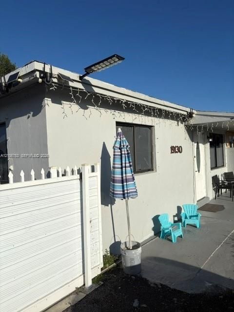 Exterior featuring smooth-finish light-toned siding, white picket fencing, and a mounted solar-powered LED floodlight