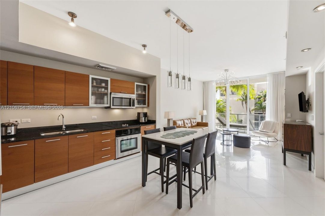 Modern kitchen featuring wood-finish cabinetry, dark solid-surface countertops, built-in stainless steel appliances