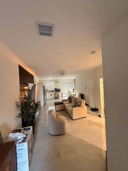 Open-concept interior featuring large-format tile flooring, recessed ceiling lighting, and a dark accent wall