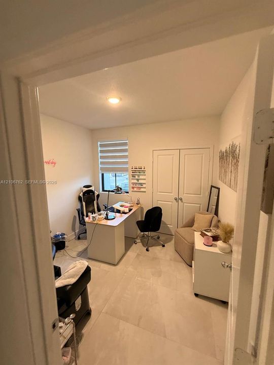 Interior room featuring large-format neutral tile flooring, dual-panel closet doors, and a window with adjustable horizontal blinds