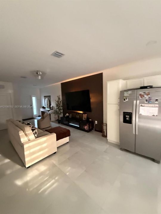 Large-format light-toned tile flooring, recessed ceiling lighting, and a distinct feature wall with integrated ambient lighting