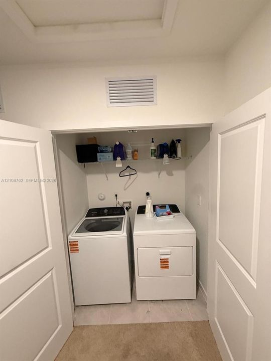 Laundry closet featuring dual paneled doors and an overhead wire shelving unit