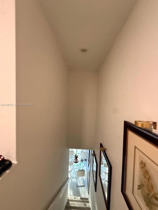 Stairwell featuring neutral wall finishes, carpeted steps, and brass-finish wall-mounted light fixtures