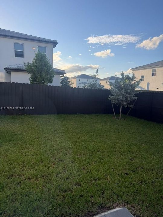 Private backyard featuring a grass lawn, perimeter wood fencing, and established landscape trees