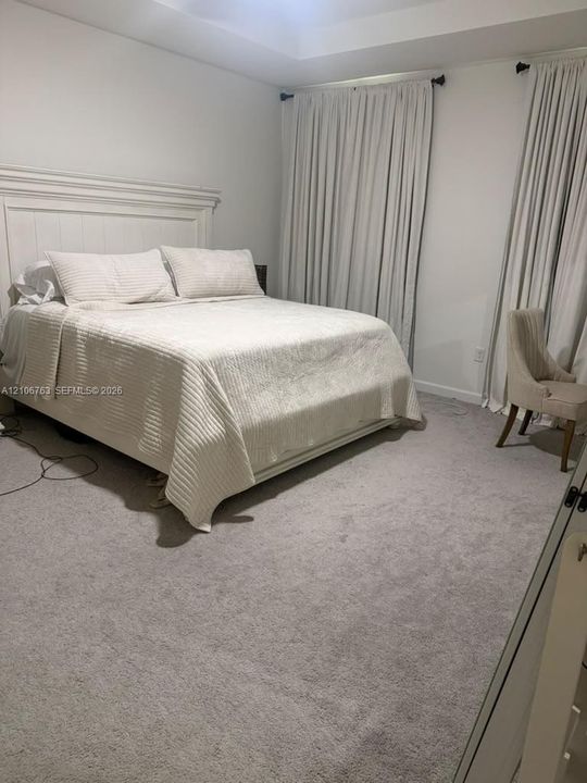 Room featuring a tray ceiling, wall-to-wall carpeting, and floor-to-ceiling window treatments