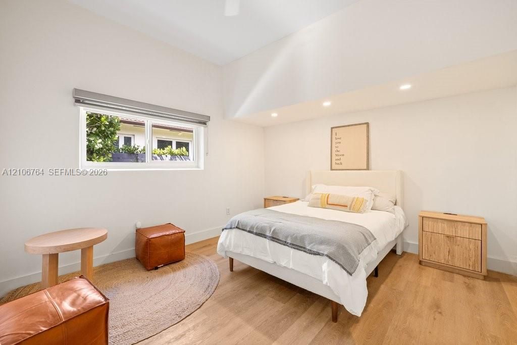 High-ceiling room featuring recessed lighting, wood-finish flooring, and a window with a roller shade