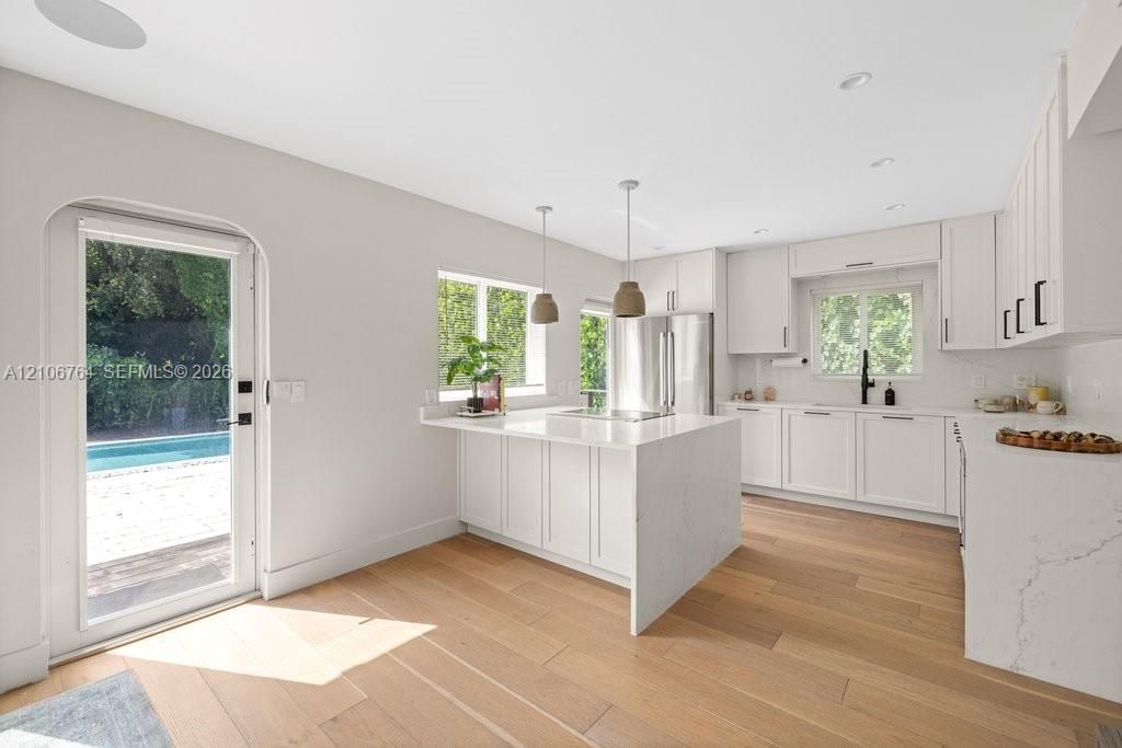 Kitchen featuring white cabinetry, quartz countertops with a waterfall edge, wood-finish flooring, recessed lighting, and arched glass-panel door