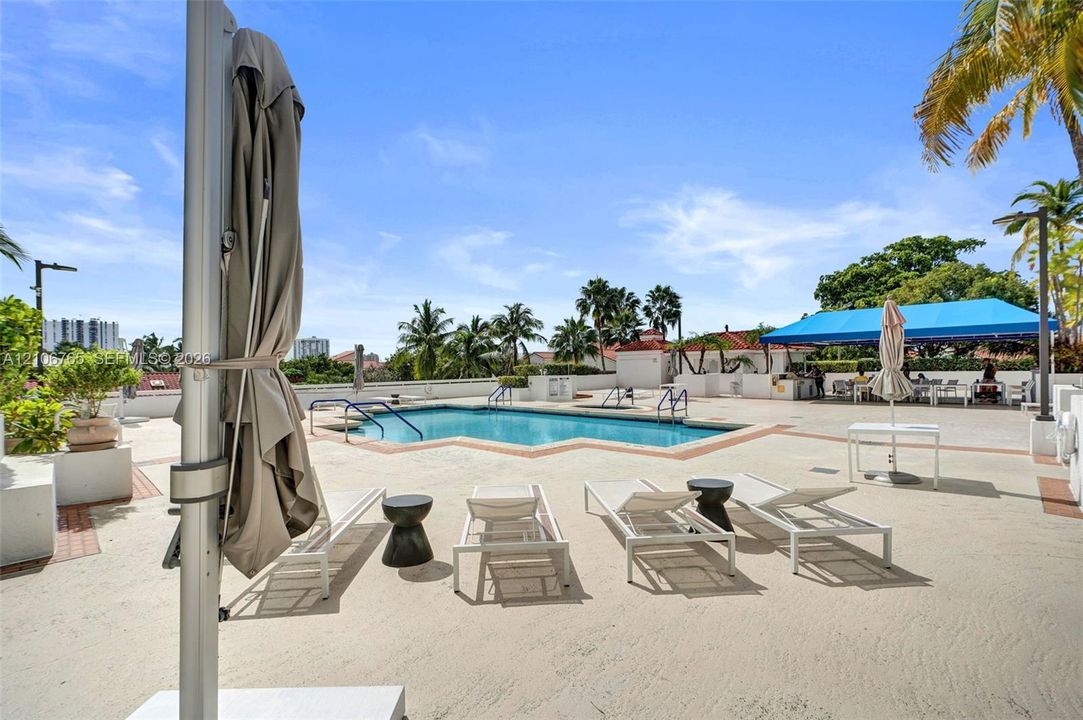 Swimming pool, expansive concrete deck, built-in structural shaded area, and perimeter masonry walls