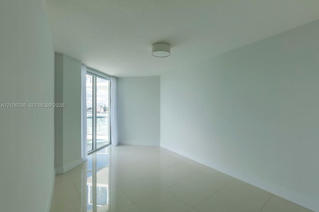 Expansive room featuring neutral wall tones, large-format tile flooring, a minimalist ceiling-mounted light fixture, and floor-to-ceiling glass sliding doors