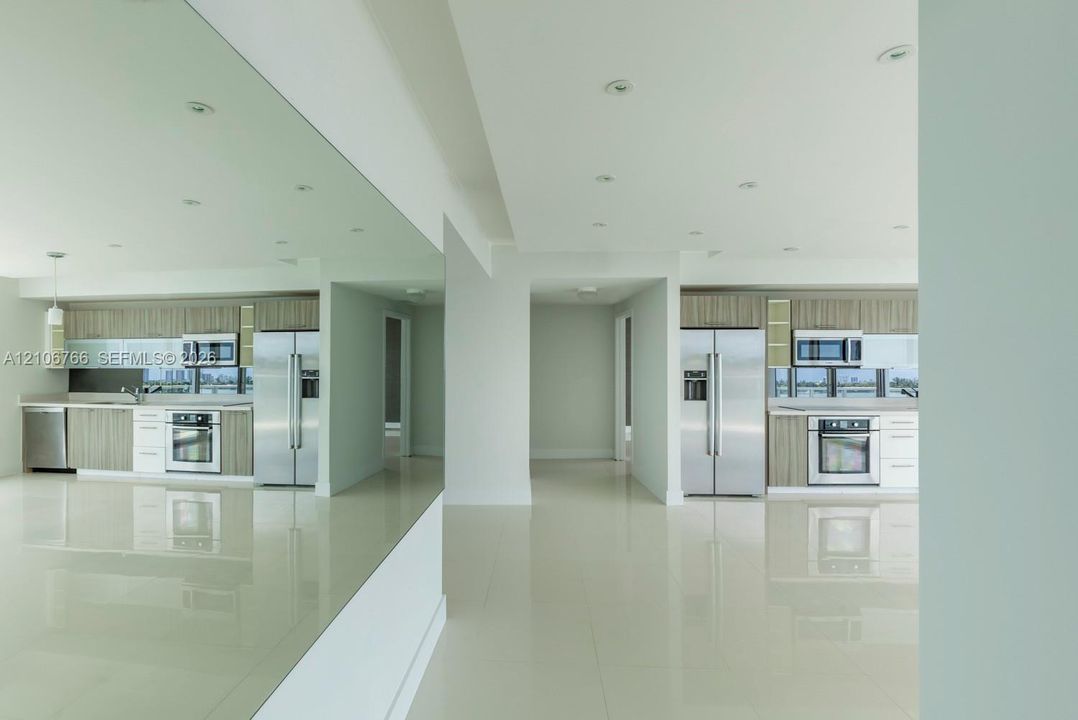 Kitchen featuring flat-panel cabinetry, stainless steel appliances, polished flooring, recessed lighting, and a full-height wall mirror