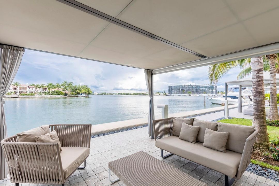 Covered patio featuring paver flooring, a tension-fabric canopy system, and direct waterfront access