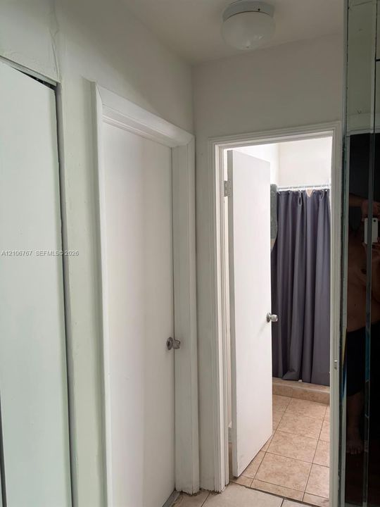 Hallway featuring mirrored closet doors, solid-core interior doors, and ceramic tile flooring