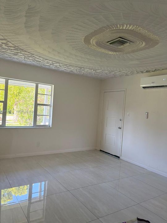 Interior space featuring large-format polished tile flooring, a decorative textured ceiling, and a wall-mounted ductless mini-split climate control system