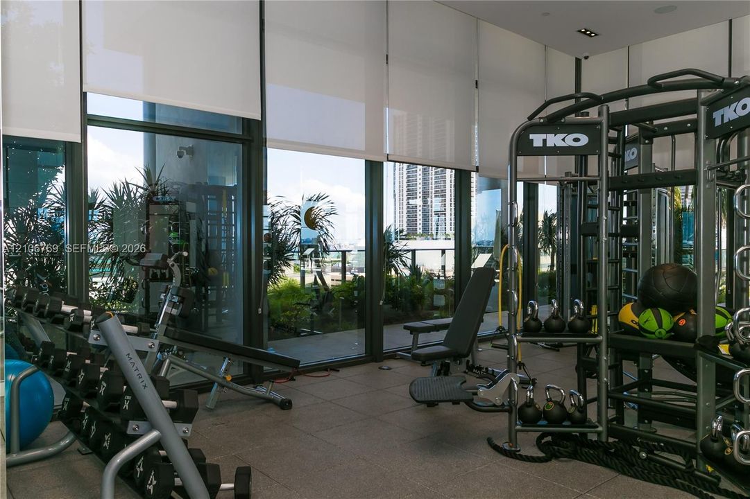 Floor-to-ceiling glass windows with retractable roller shades, large-format tile flooring, and recessed ceiling lighting