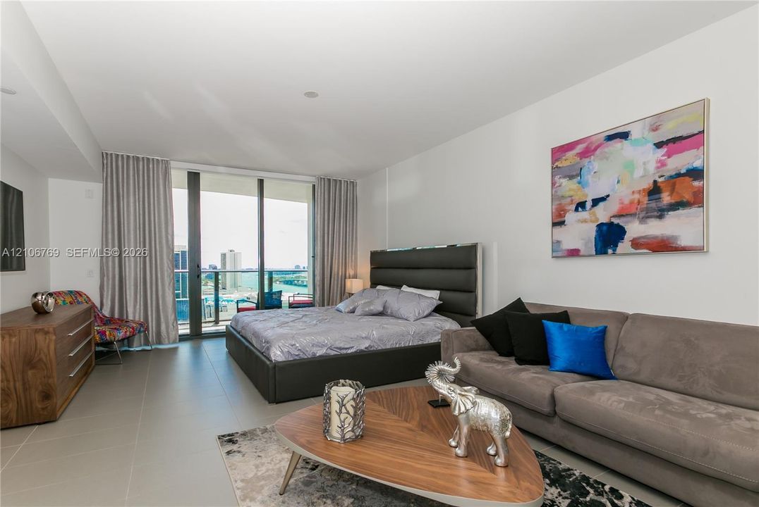 Large-format tile flooring, floor-to-ceiling glass sliding doors, and private balcony access
