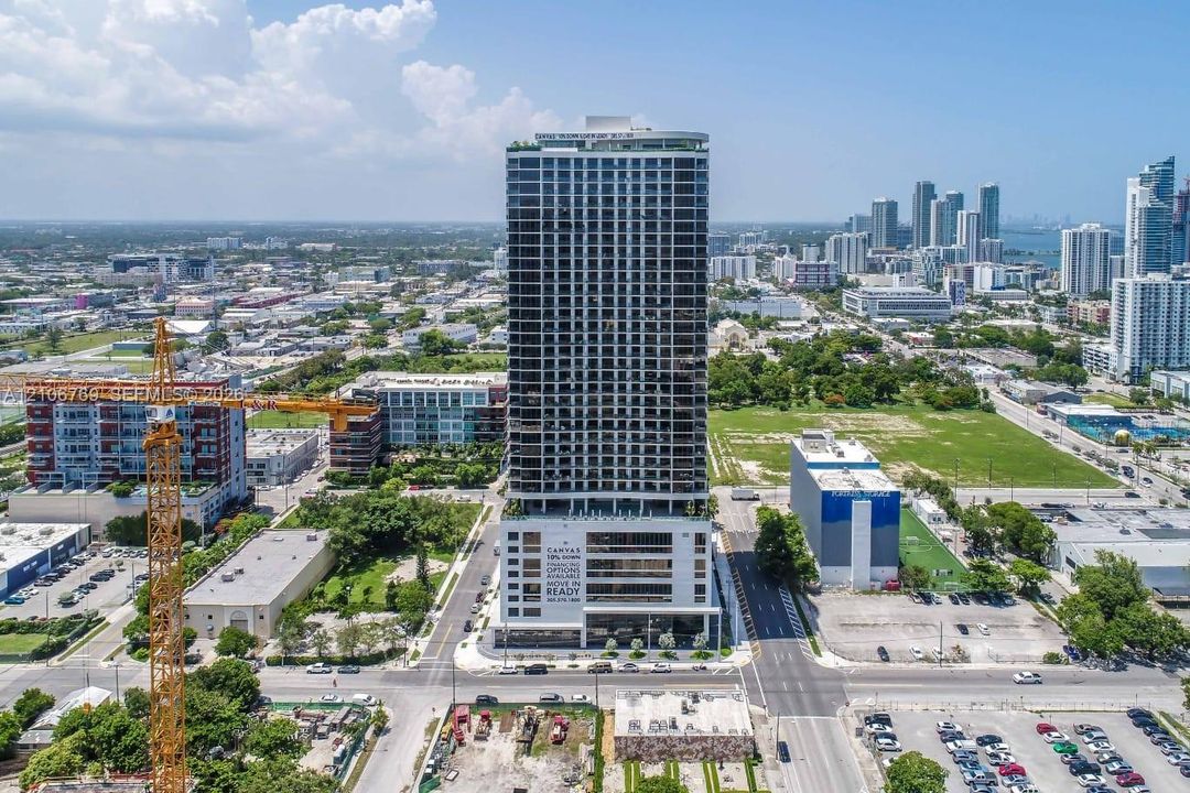 High-rise tower featuring a glass facade, multiple recessed balconies, and a rooftop terrace