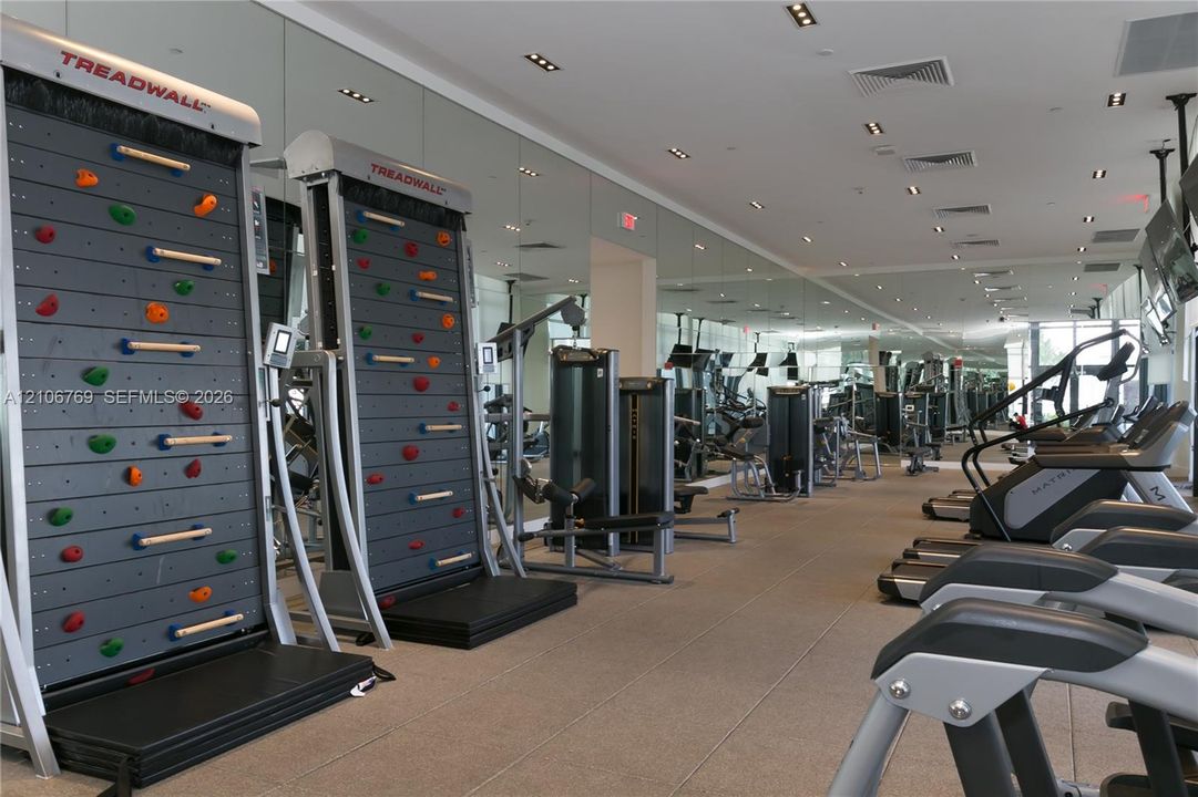 Fitness facility featuring floor-to-ceiling mirrored walls, recessed lighting, and rubberized flooring