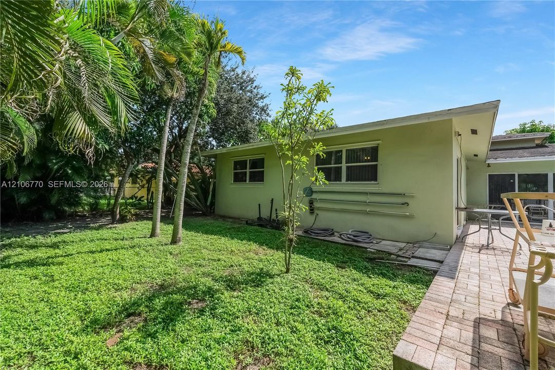 Exterior backyard space featuring a paver patio, established palm trees, and mature landscaping