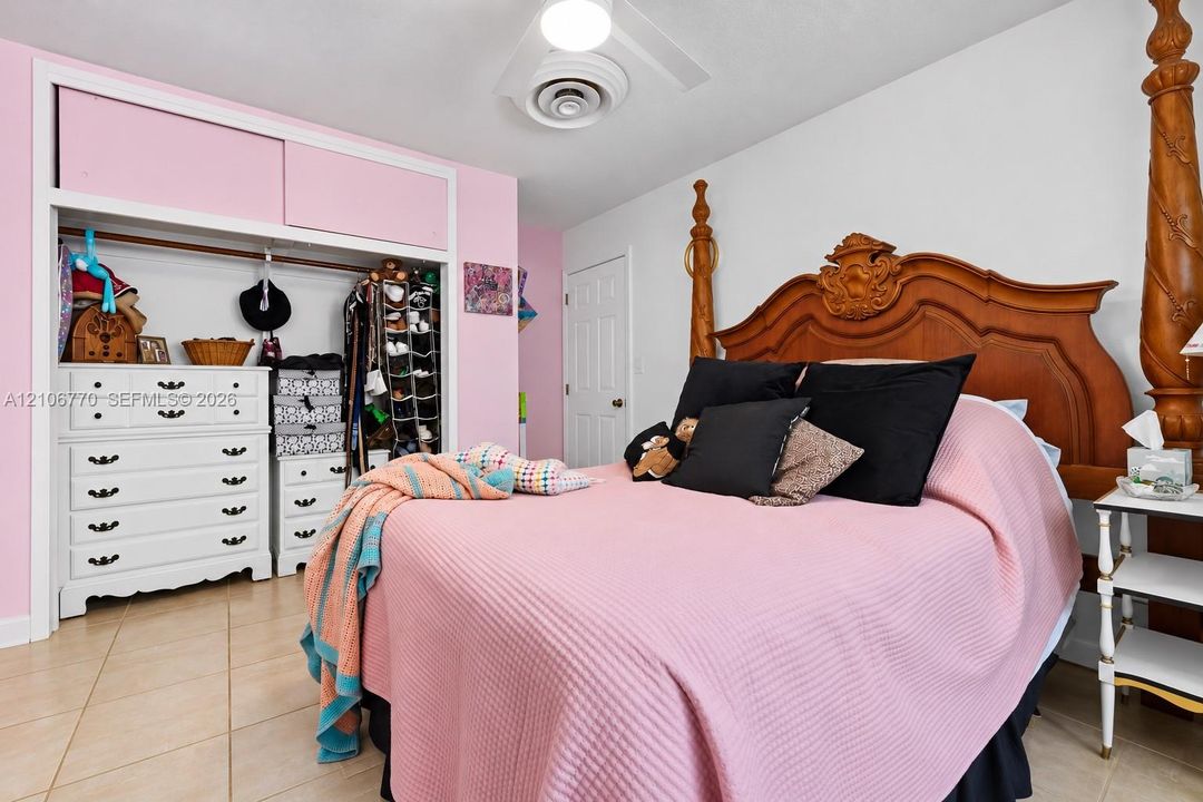 Bedroom featuring tile flooring, sliding door closet with integrated upper storage cabinets, and a central ceiling light fixture
