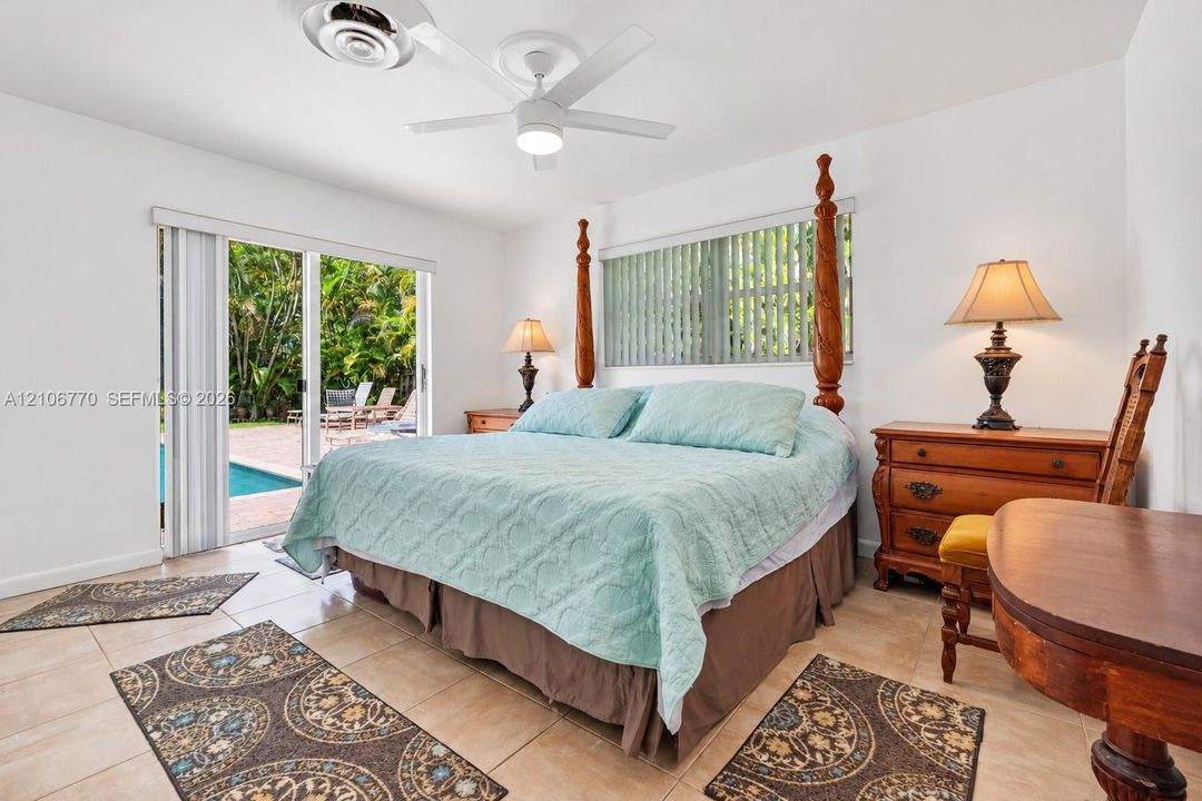 Neutral-tone tile flooring, white-finish ceiling fan, and sliding glass doors with access to an exterior brick-paved patio and pool area