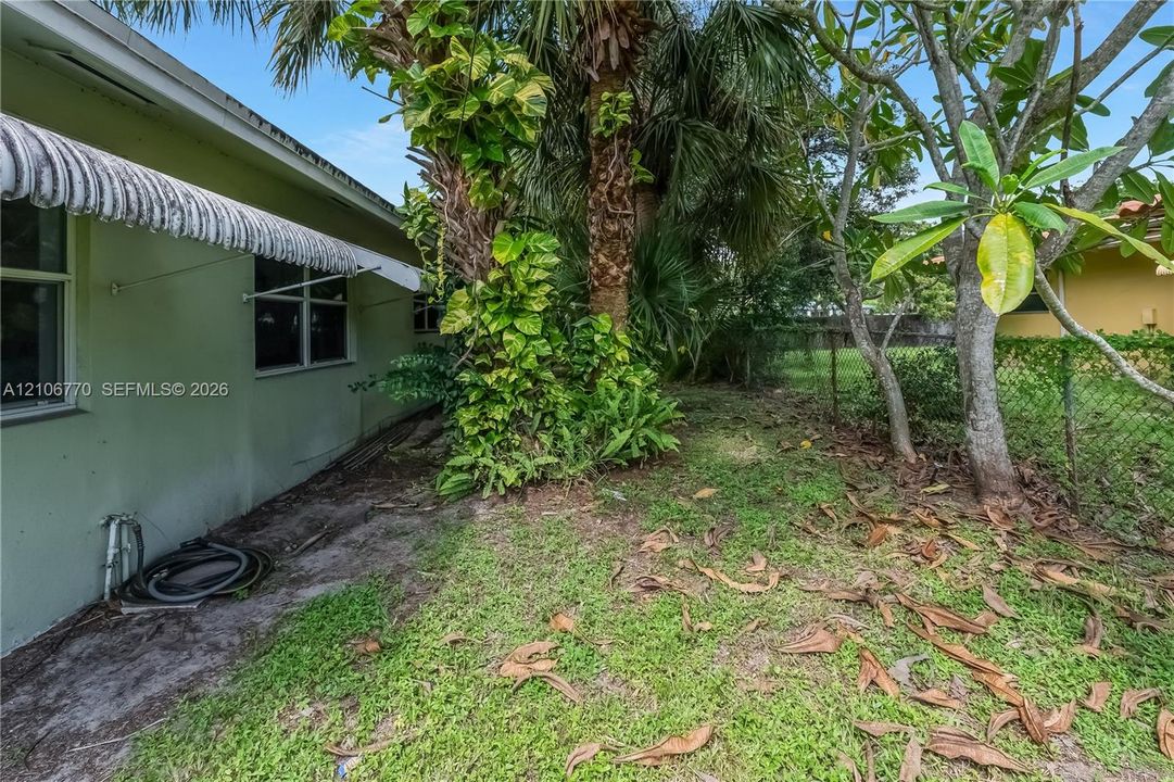Exterior wall featuring fixed metal awnings, multi-pane windows, and mature palm trees