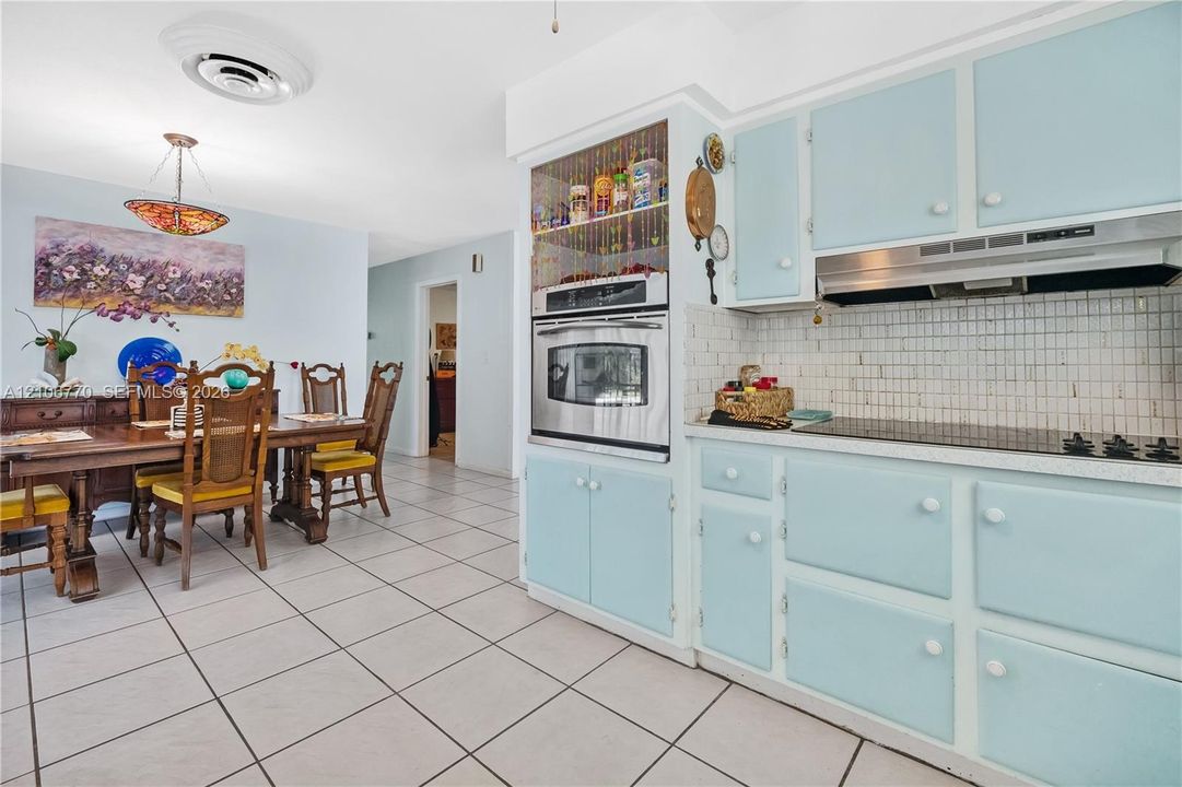 Kitchen featuring custom blue cabinetry, built-in stainless steel wall oven, ceramic tile backsplash, and ceramic tile flooring