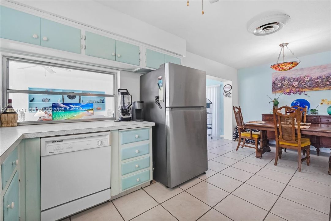 Kitchen featuring custom cabinetry, stainless steel refrigerator, white dishwasher, and tile flooring