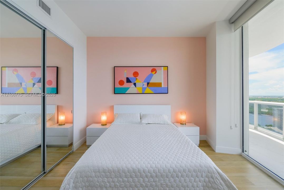 Floor-to-ceiling glass sliding doors, wood-finish flooring, mirrored sliding closet doors, and access to a private balcony