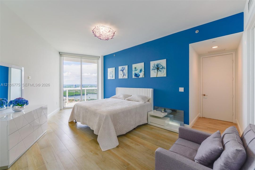 Floor-to-ceiling sliding glass doors, wood-finish flooring, accent wall, and decorative overhead lighting fixture